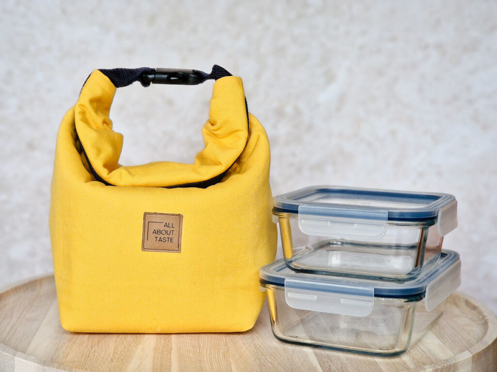 Eine Thermo Lunch Bag aus gelben Canvas steht auf einem hellen Holztisch.